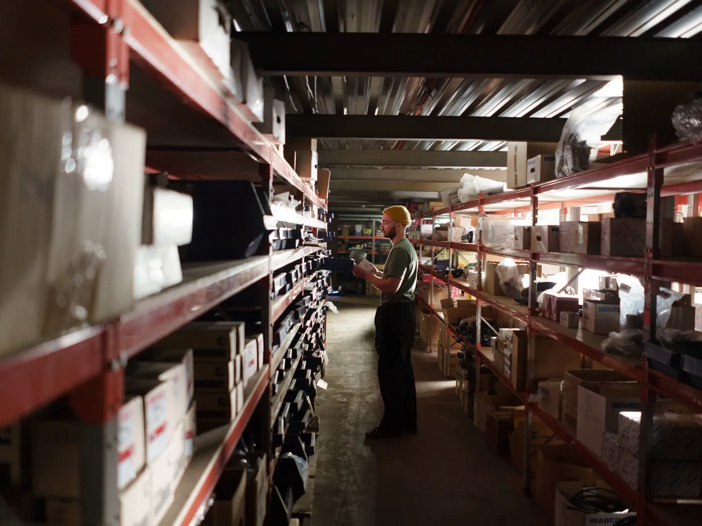 Allée de stockage de pièces détachées, cartons et références alignés sur les racks